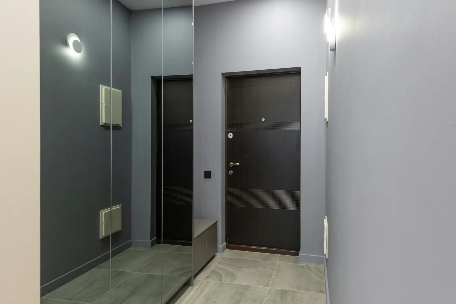 Lối đi rộng rãi với tường xám nhẹ và tủ âm tường cánh gương đặt trên sàn gỗ, giúp nhân đôi ánh sáng và không gian. | Thiết kế nội thất 24