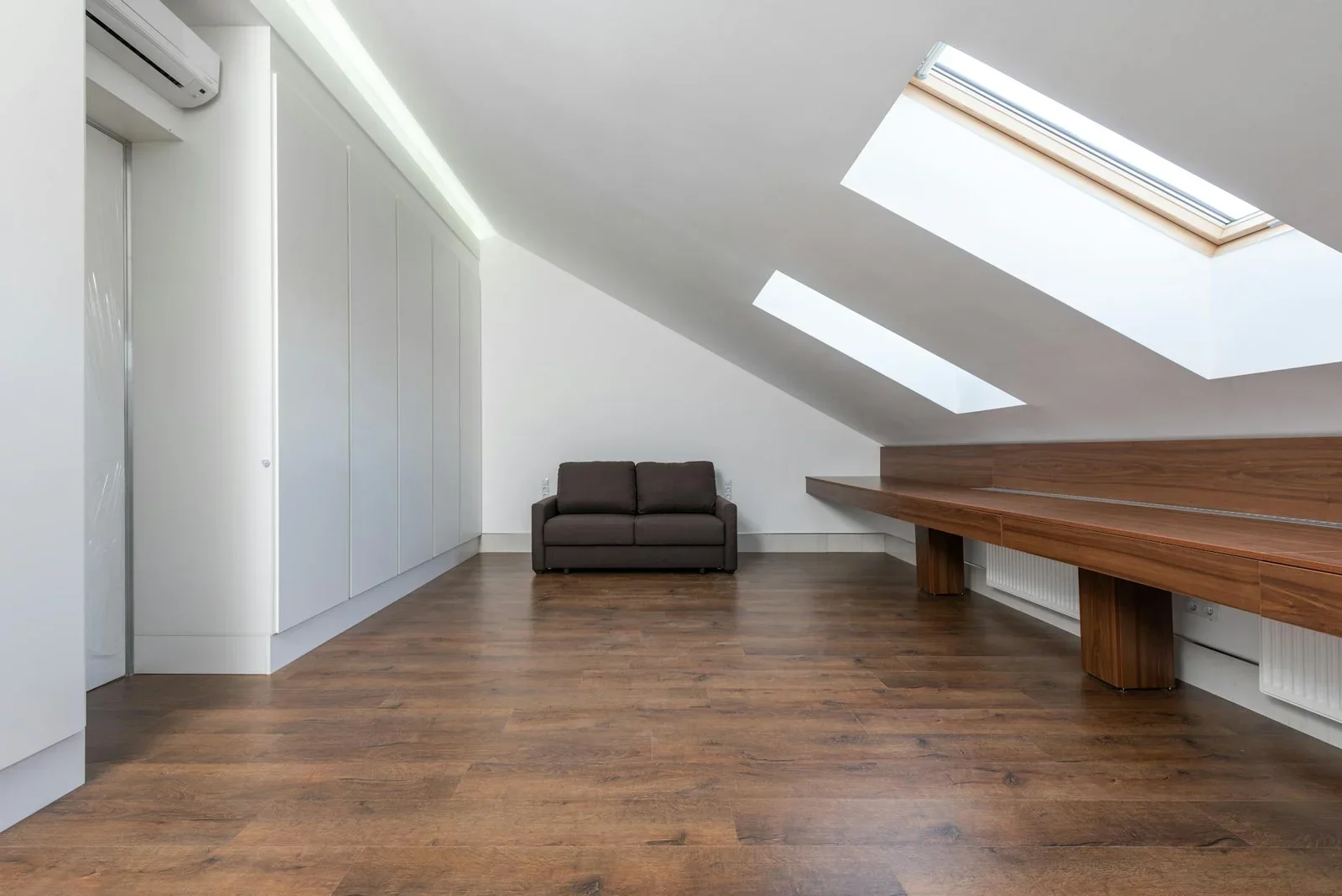 Tầng áp mái penthouse rộng rãi với cửa trần đón nắng, sàn gỗ ấm áp cùng sofa nâu tạo góc sinh hoạt gia đình thân mật. | Thiết kế nội thất 24