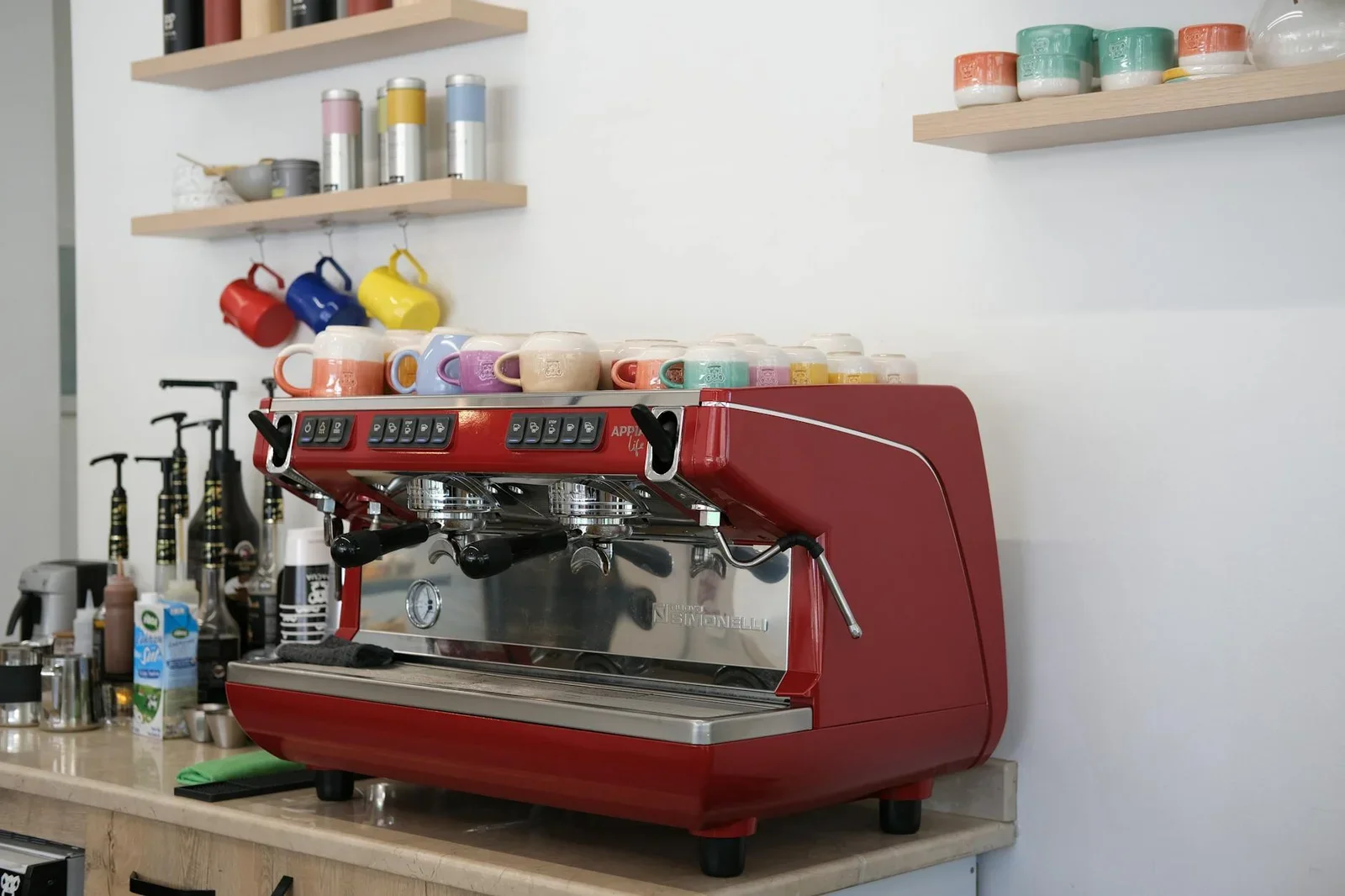 Góc pha cà phê tại gia với máy espresso đỏ nổi bật, kệ treo ly tách đa sắc tạo cảm hứng sáng tạo mỗi sáng. | Thiết kế nội thất 24