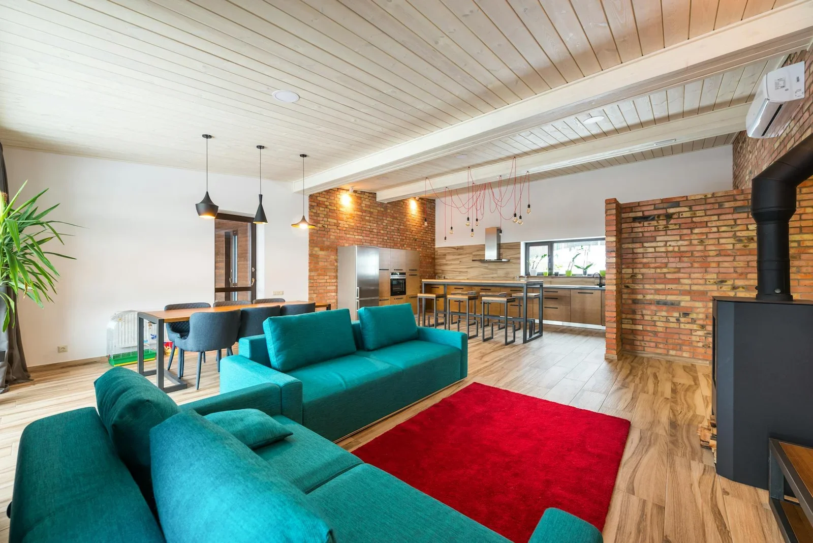 Phòng khách hiện đại gây ấn tượng với tường gạch mộc, sofa xanh ngọc cùng thảm đỏ tạo điểm nhấn ấm áp và cá tính. | Thiết kế nội thất 24