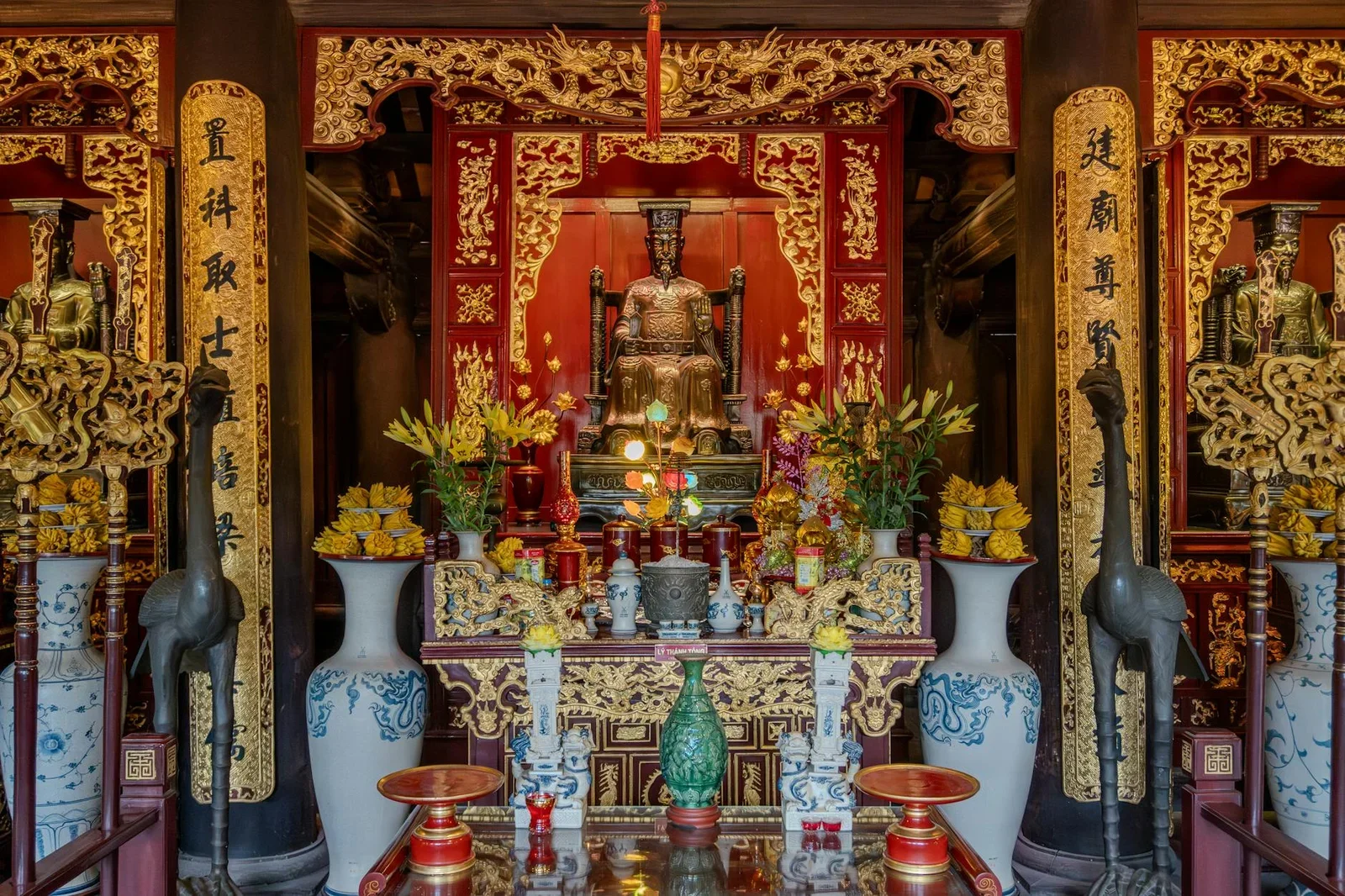 Bàn thờ trang trí cầu kỳ với điểm nhấn mạ vàng, bình hoa và tượng thờ, ánh sáng tập trung làm nổi bật vẻ đẹp uy nghi. | Thiết kế nội thất 24