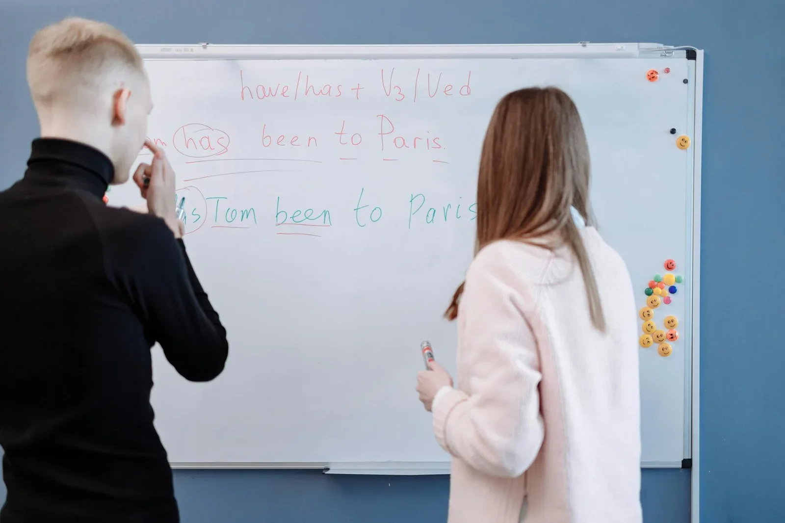Hai học viên cùng nghiên cứu ngữ pháp tiếng Anh tại bảng trắng, thể hiện tính ứng dụng cao của thiết kế phòng học. | Thiết kế nội thất 24